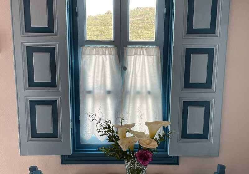 Το τραπέζι δίπλα στο παράθυρο με τα γαλάζια παντζούρια